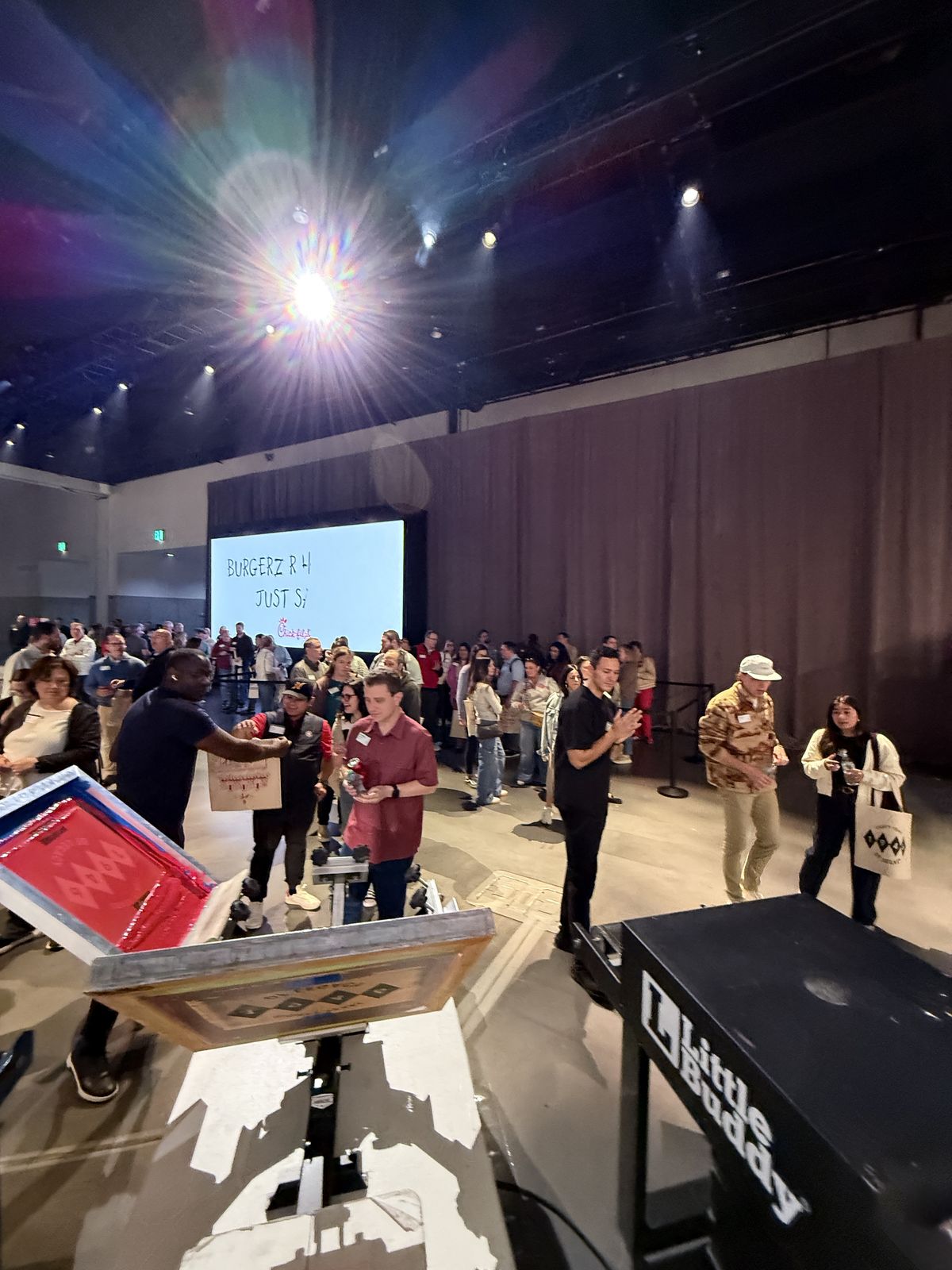 Live screen printing station with attendees mingling in a large ballroom at a brand conference